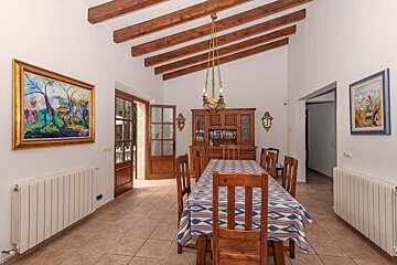 A dining room with a table and chairs and a painting on the wall