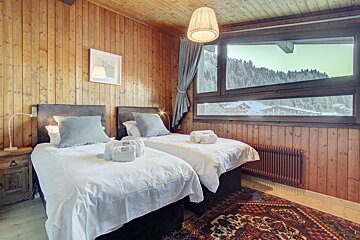 A bedroom with two beds and a window with a view of the mountains