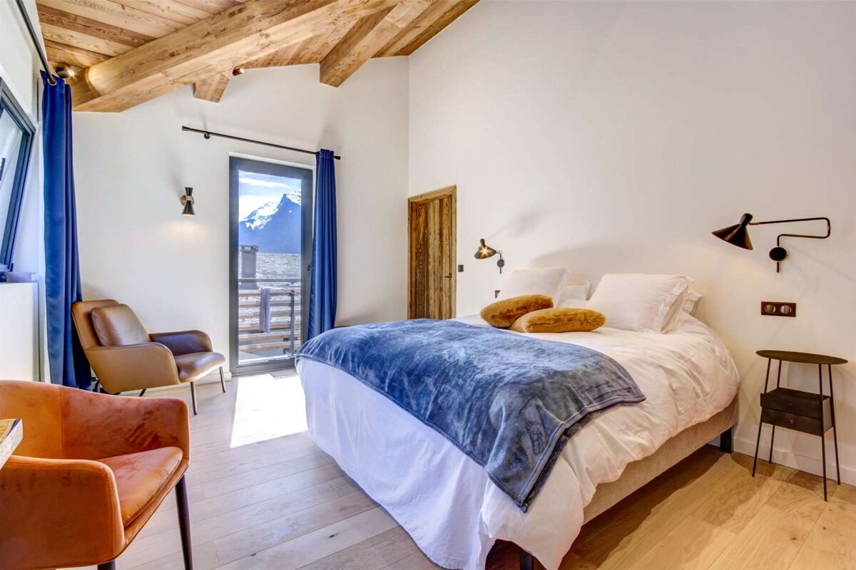 A bedroom with a large bed and a chair