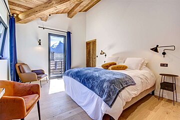 A bedroom with a large bed and a chair