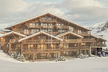 A large, multi-story wooden chalet surrounded by snow in a mountainous winter landscape.