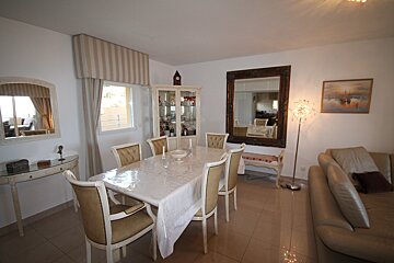 A dining room with a table and chairs and a mirror