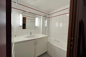 A bathroom with white tiles and a sink and bathtub