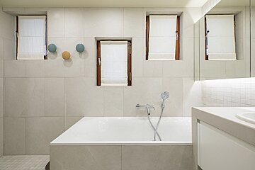 A bathroom with a bathtub and three windows