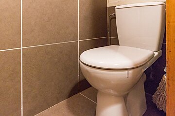 A white toilet sits in a bathroom next to a mop