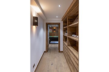 A hallway with wooden shelves leading to a pool table