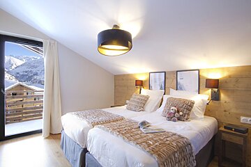 A bedroom with two beds and a teddy bear on the bed
