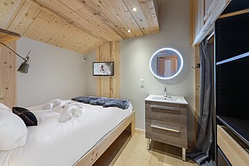 A small bedroom with a bed and a sink