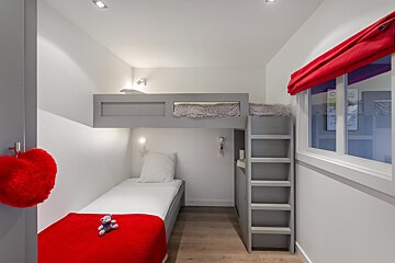 A bedroom with a bunk bed and a teddy bear on the bed