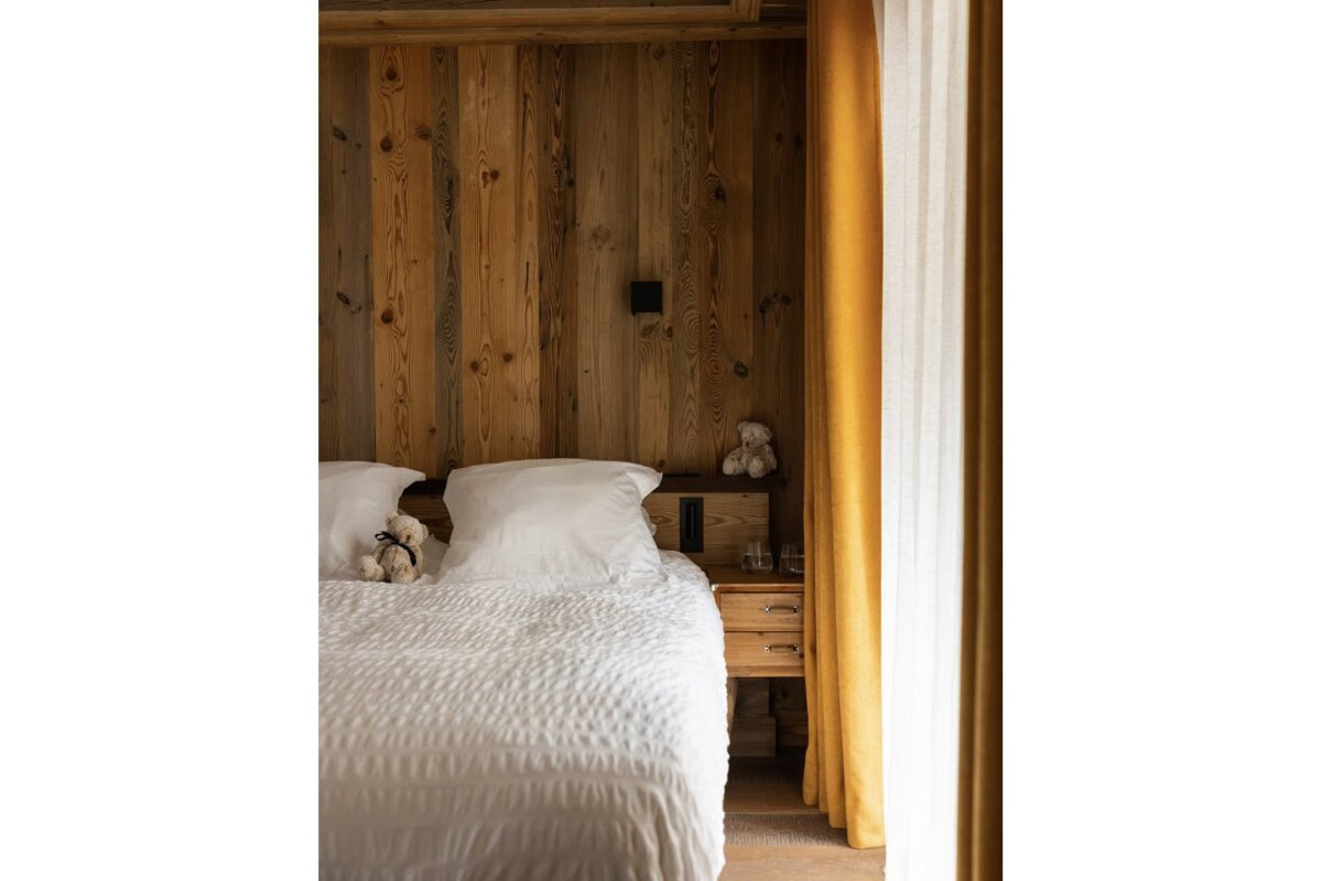 A bedroom with a teddy bear on the bed