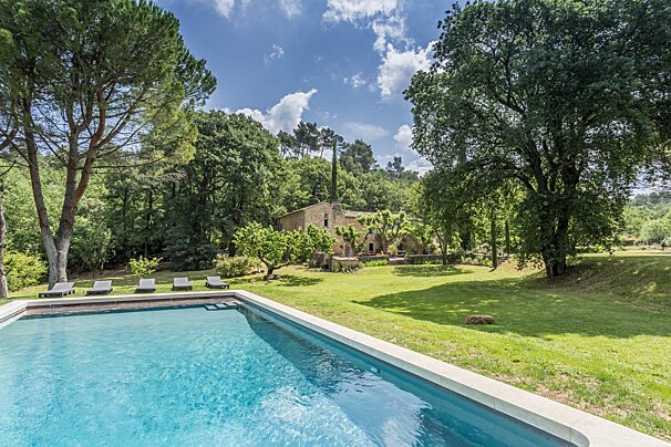 A large swimming pool surrounded by trees and lawn chairs