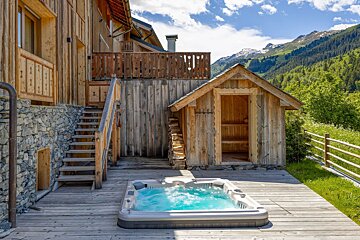 A hot tub sits on a wooden deck in front of a wooden building