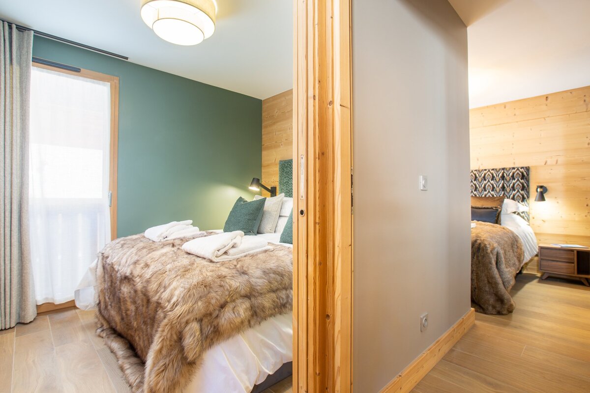 A bedroom with two beds and a green wall