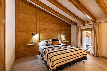 A bedroom with wooden walls and a bed with a striped blanket