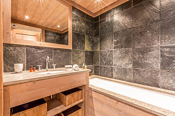 A kitchen with wooden cabinets and a clock on the wall that has roman numerals