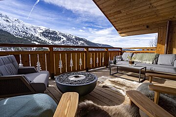 A balcony with a fire pit and mountains in the background