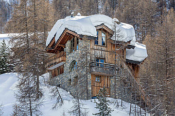 A snow covered roof of a house in the woods