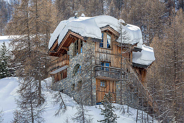 A snow covered roof of a house in the woods