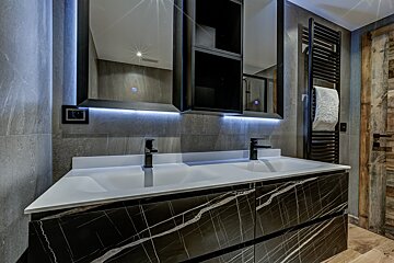 A bathroom with two sinks a mirror and a towel rack