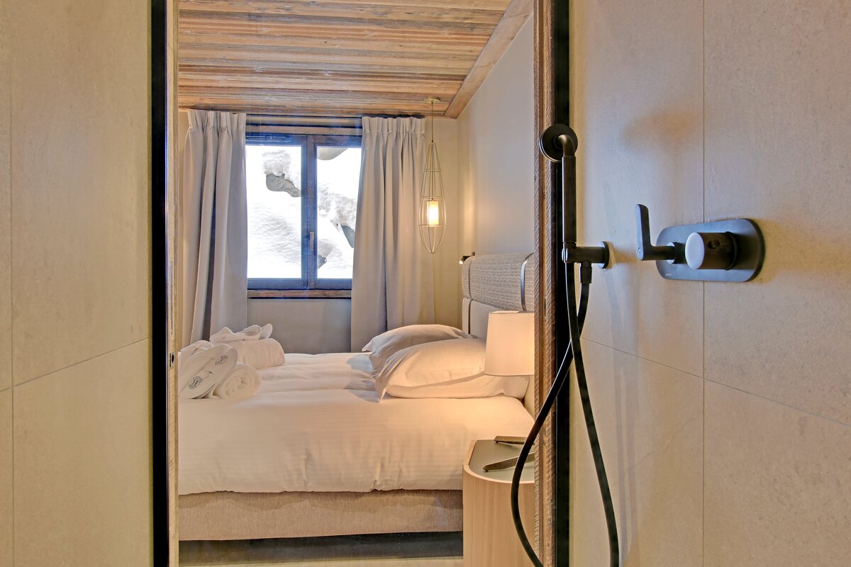 A bedroom with a shower and a bed with white sheets