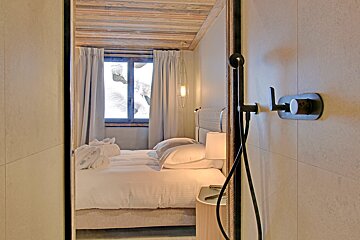 A bedroom with a shower and a bed with white sheets