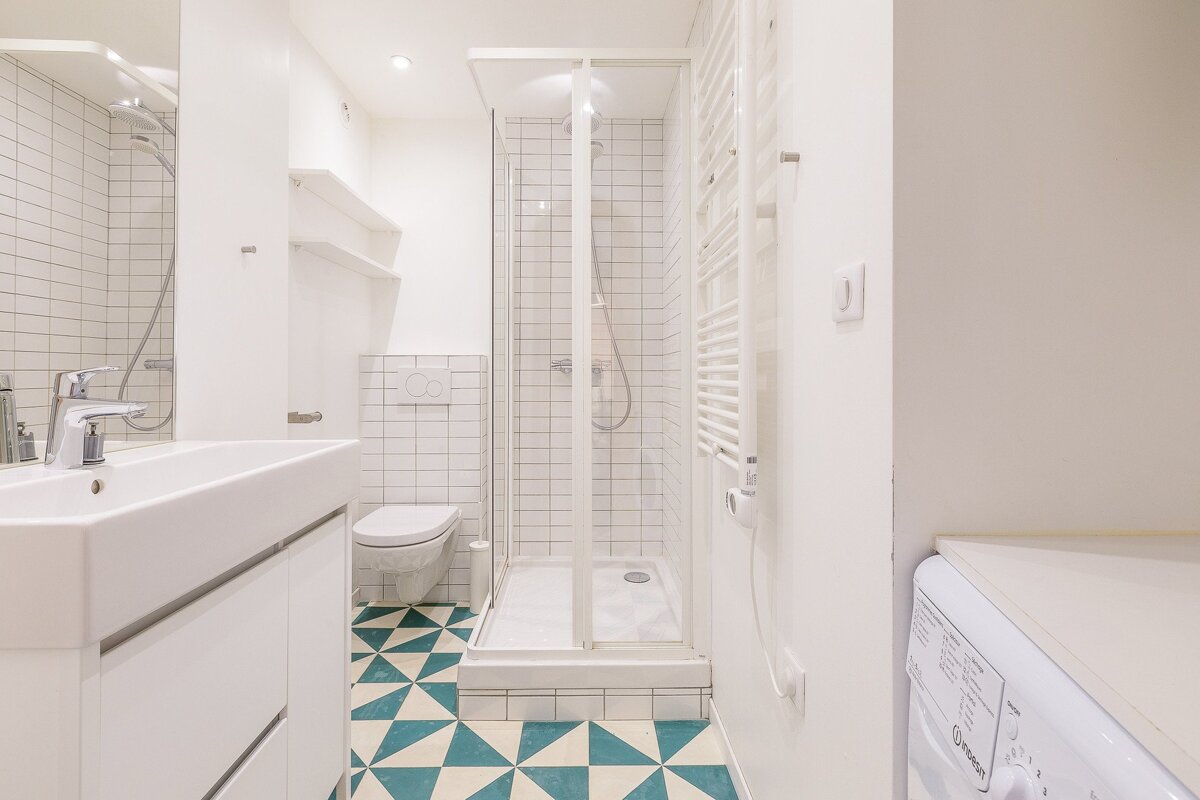 A bathroom with a washing machine and a toilet