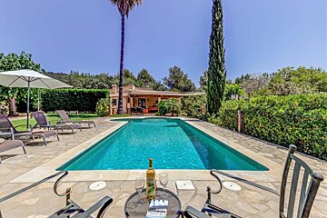 A bottle of wine sits on a table next to a swimming pool