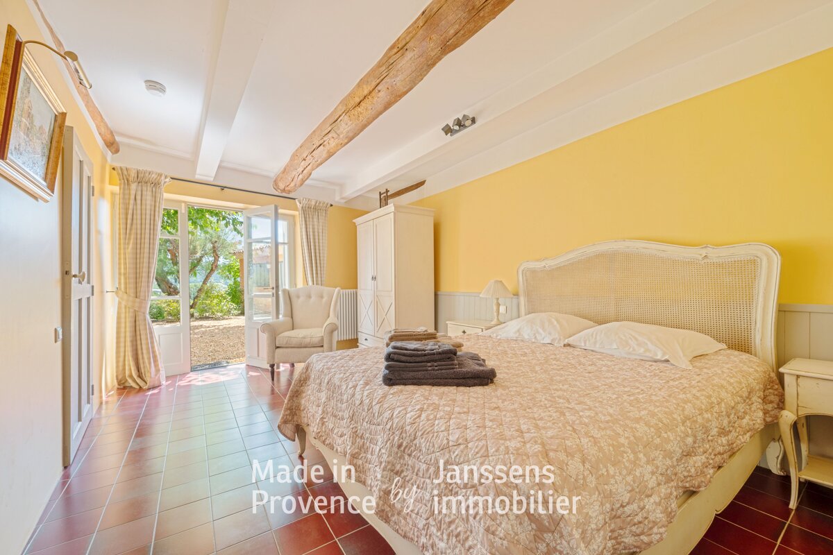 A bedroom with yellow walls and a bed made in provence by janssens immobilier