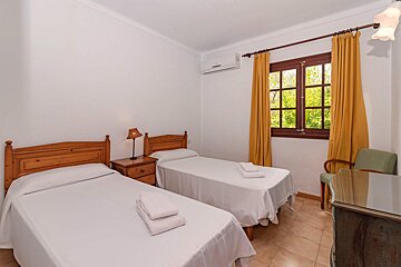 A bedroom with two twin beds and a window