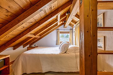 A bedroom with a wooden ceiling and a bed