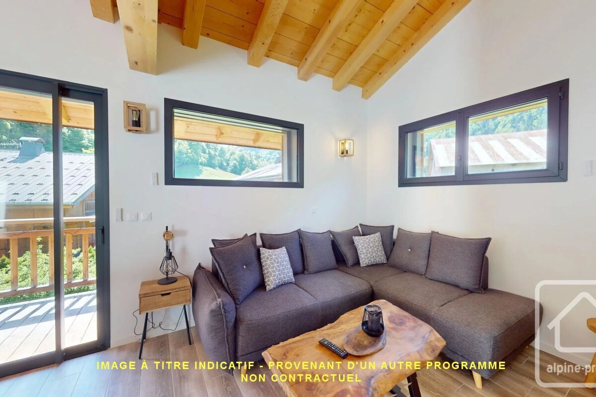 Cozy chalet living room with a grey sectional sofa, live-edge wood coffee table, exposed ceiling beams, and scenic window views.
