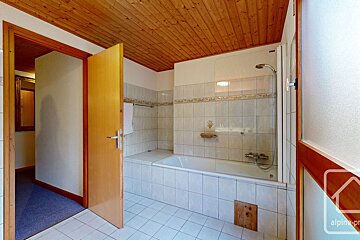 A bathroom with a bathtub and a shower with the word alpine on the wall