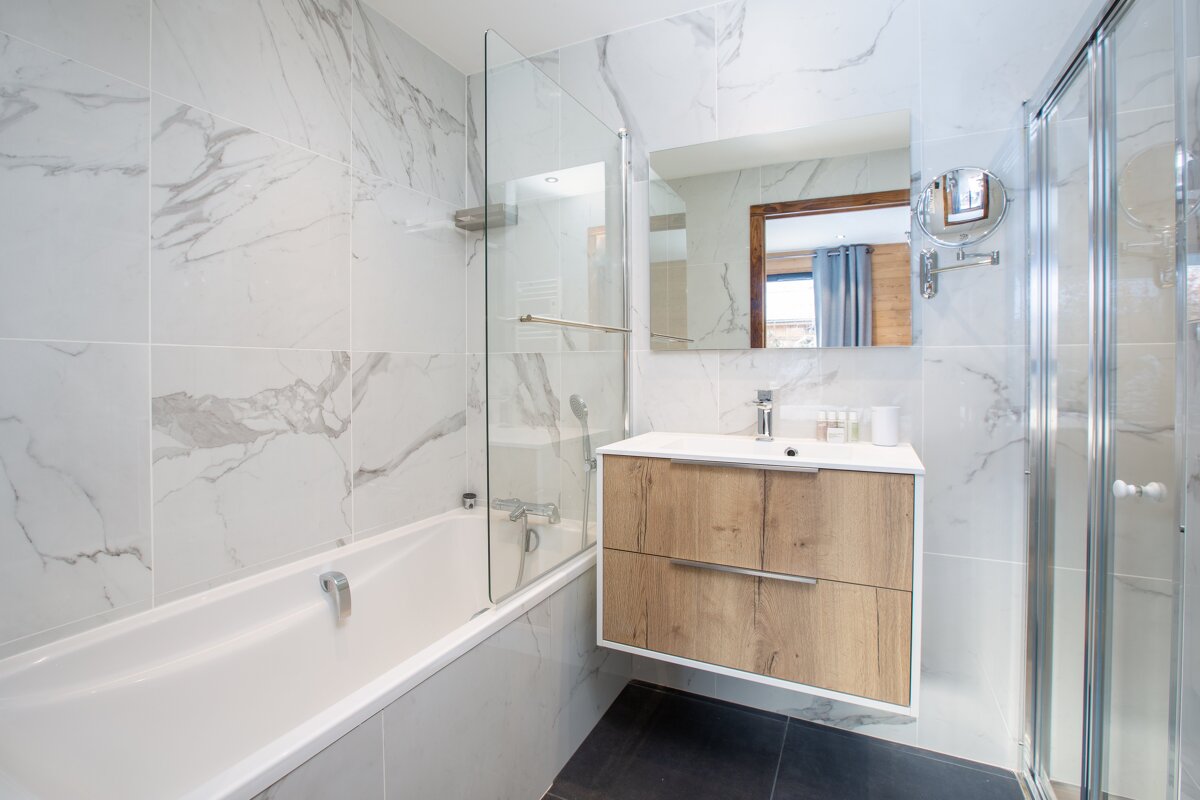 A bathroom with marble tiles and a wooden sink