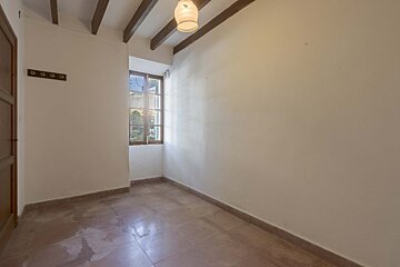 An empty room with a window and a light hanging from the ceiling