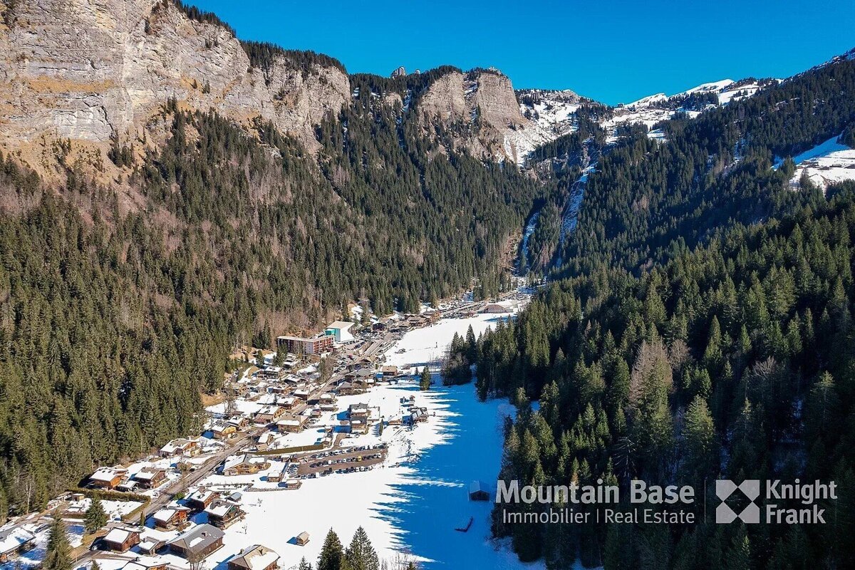 An aerial view of a snowy mountain valley with knight frank written on the bottom