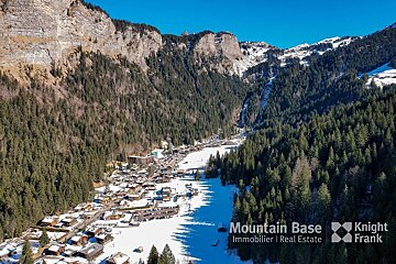 An aerial view of a snowy mountain valley with knight frank written on the bottom