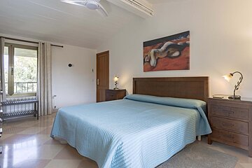 A bedroom with a painting on the wall above the bed