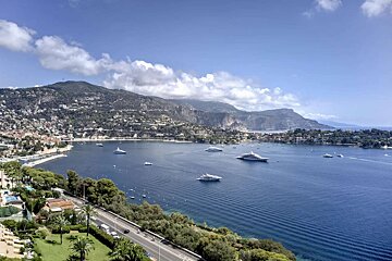 A large body of water with boats and mountains in the background
