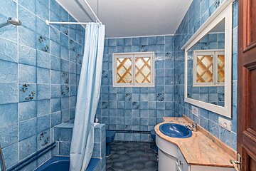 A bathroom with blue tiles and a blue shower curtain