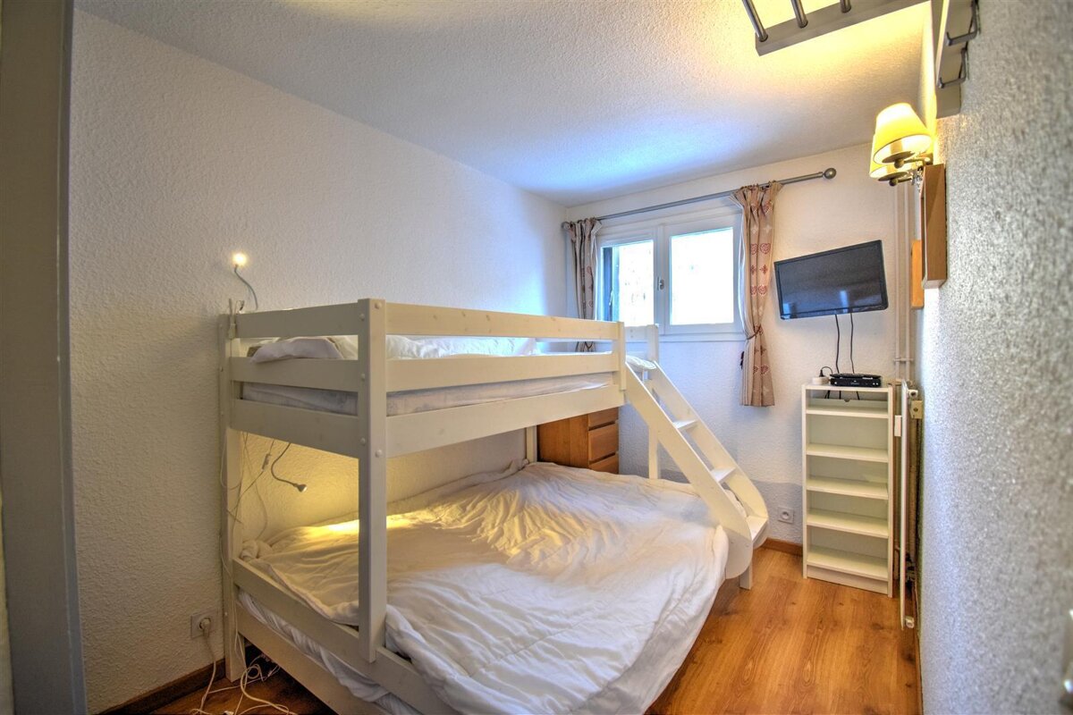 A bedroom with a bunk bed and a flat screen tv