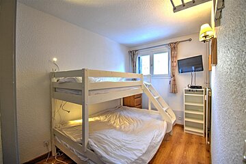 A bedroom with a bunk bed and a flat screen tv