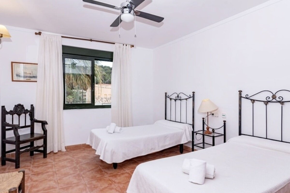 A bedroom with two beds and a ceiling fan