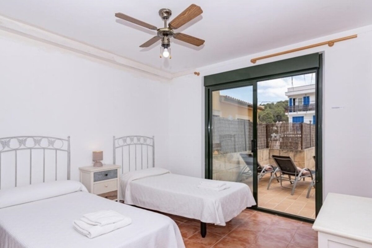A bedroom with two beds and a ceiling fan