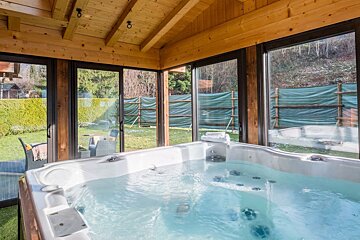 A hot tub in a room with lots of windows