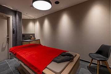 A massage table with a red blanket on it