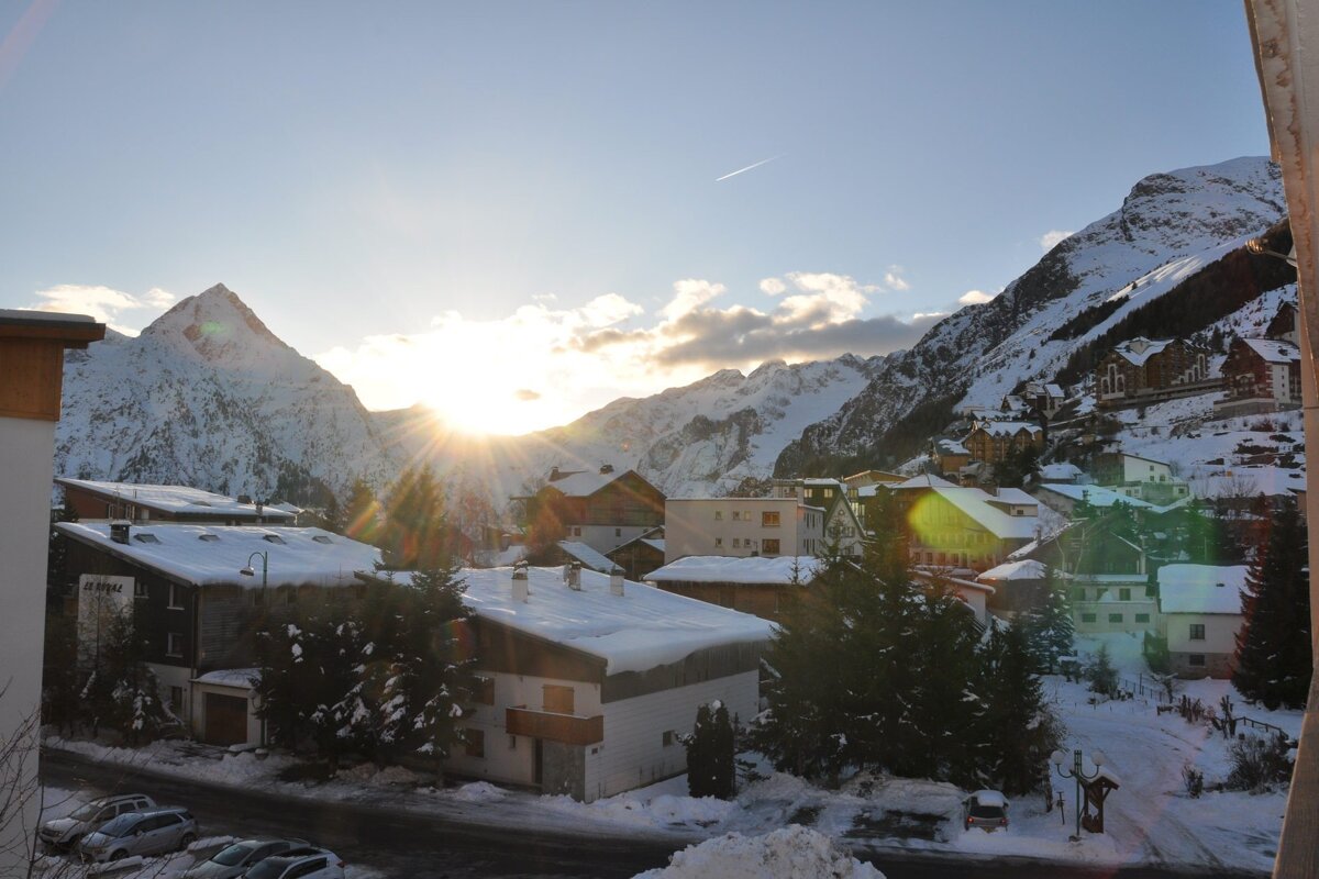 The sun shines through the clouds over a snowy town