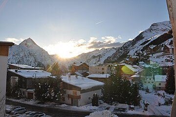 The sun shines through the clouds over a snowy town