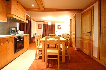 A kitchen with wooden cabinets and a table and chairs