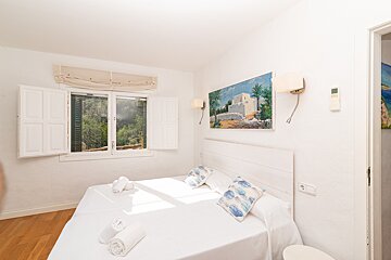 A bedroom with a painting on the wall above the bed