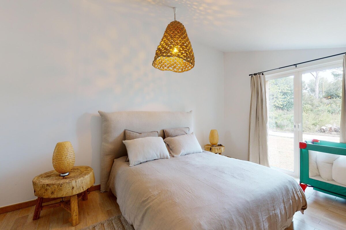 A bedroom with a bed and a lamp hanging from the ceiling